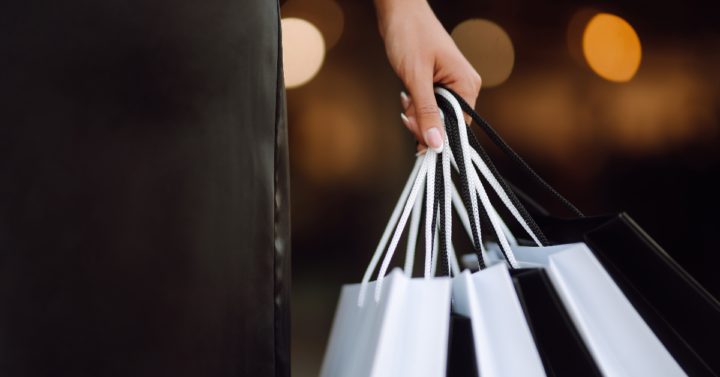 a person holding several shopping bags on a dark backround