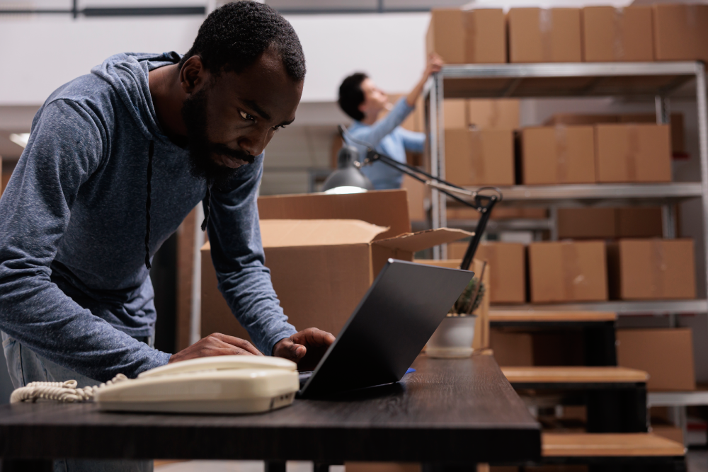 african-american-employee-looking-cargo-stock-before-start-preparing-customers-orders-working-warehouse-delivery-department-worker-checking-shipping-detalies-laptop-computer (1)