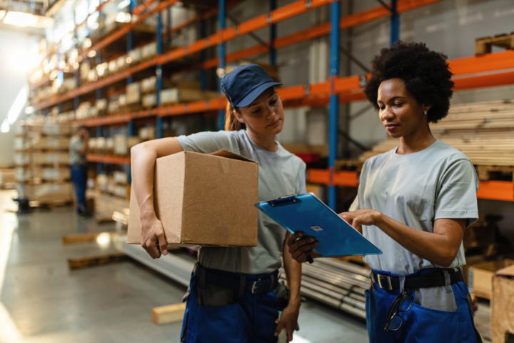 african-american-worker-her-coworker-reading-order-list-before-shipment-while-working-warehouse